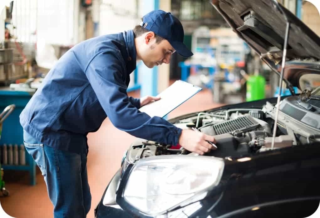 Mechaniker prüft Motorraum eines Fahrzeugs in der Werkstatt